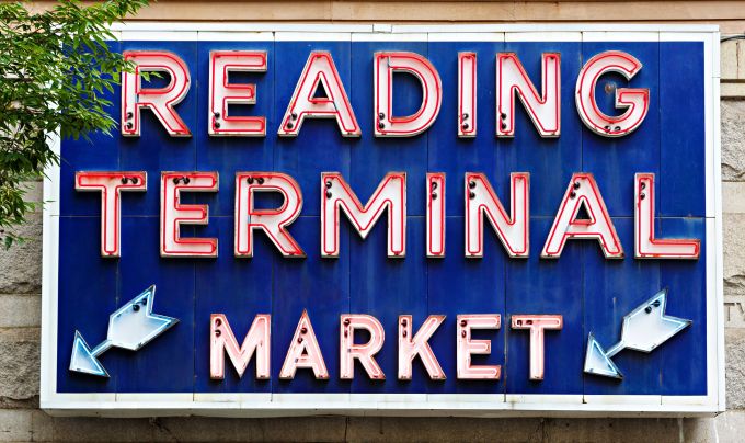 A neon sign reads Reading Terminal Market in red and white on a royal blue background